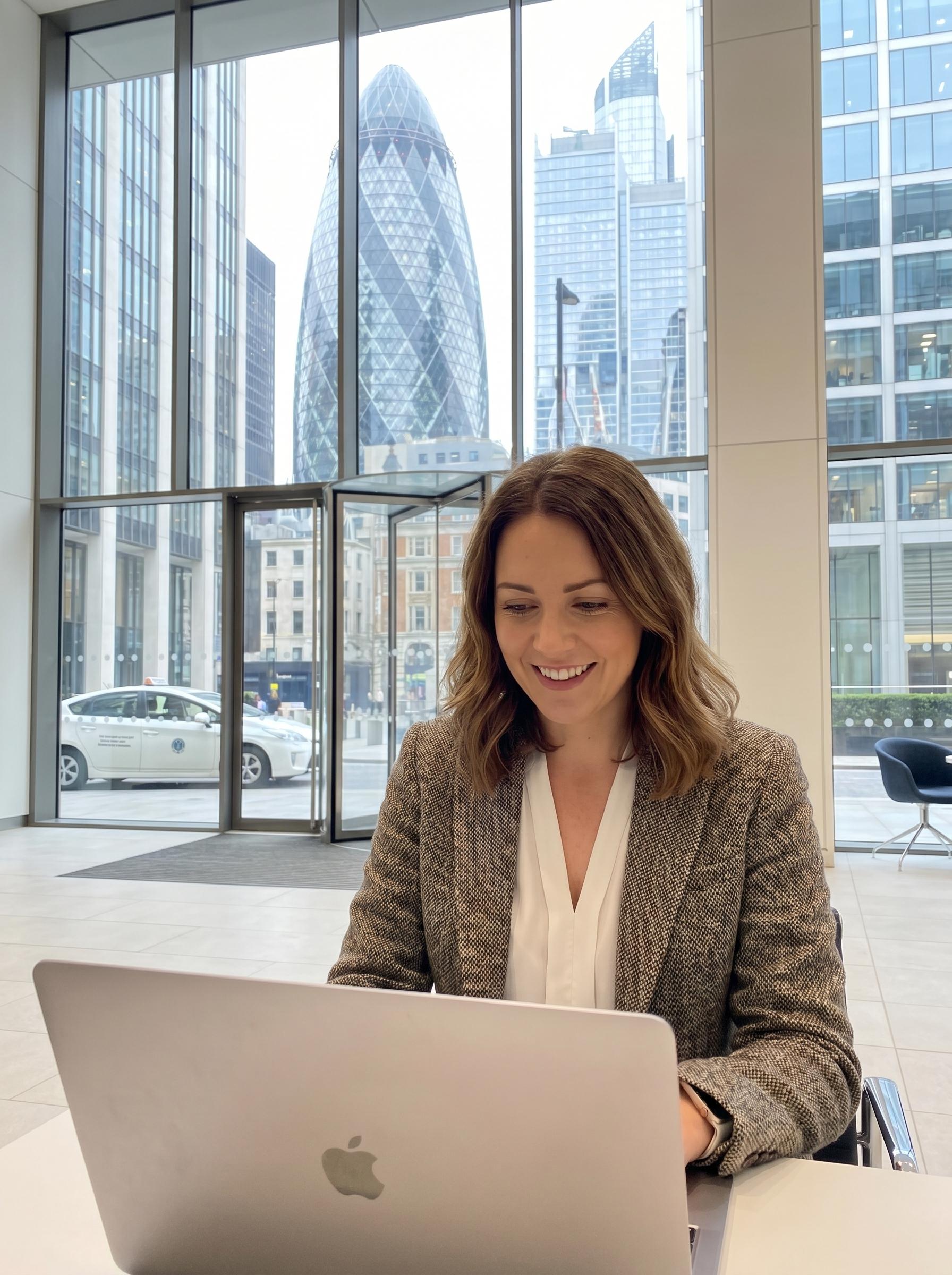 UK FM SME owner using CleanTender to qualify and draft bids on UK public-sector cleaning and facilities-management tenders, City of London office with the Gherkin in the background.